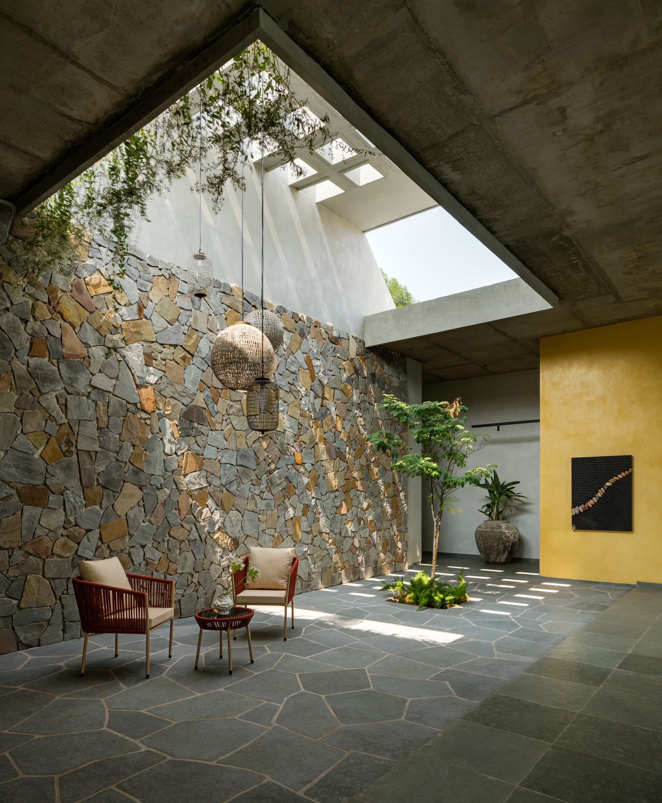 The courtyard at rest: stone wall, two cane chairs, a low table.